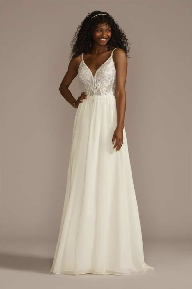 Model wears white wedding gown with spaghetti straps.