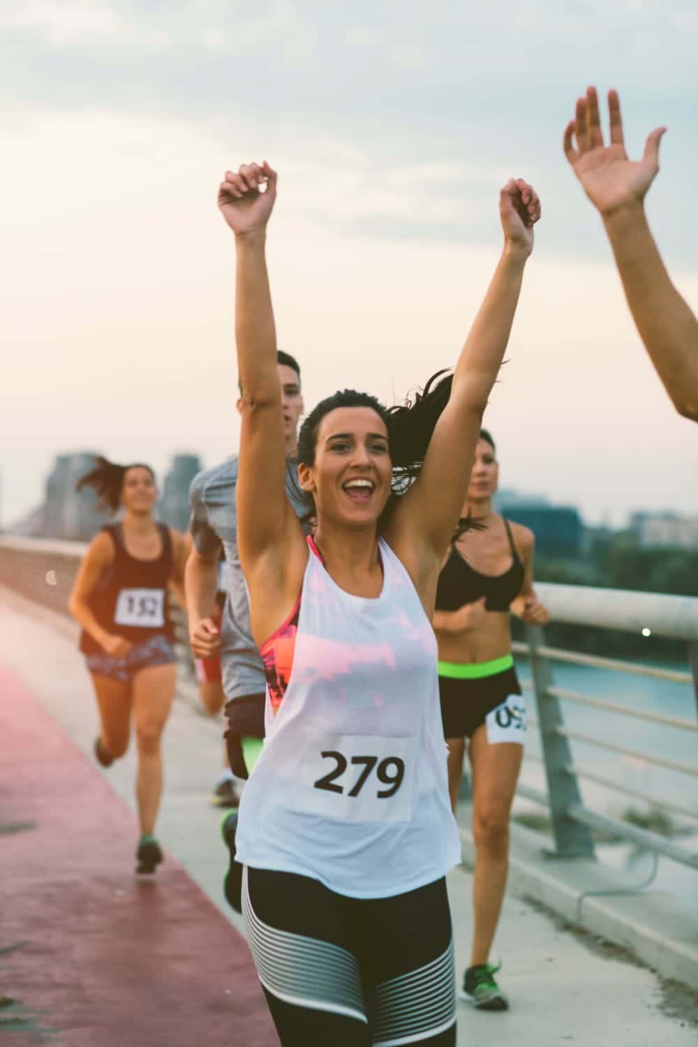 Runner in race raises arms to celebrate finish.