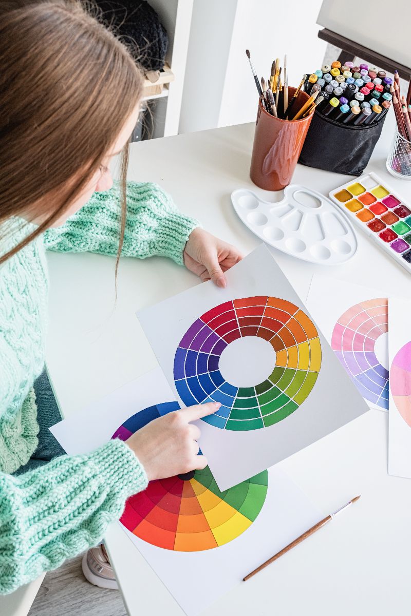 Women holds color wheel and points at shades of blue.