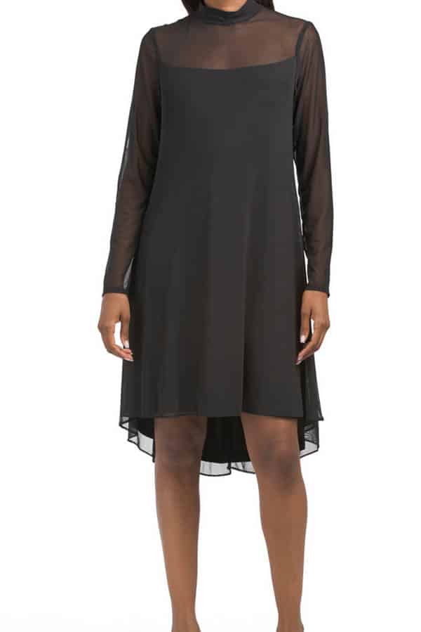 Model wearing black shift dress with sheer sleeves and neck.