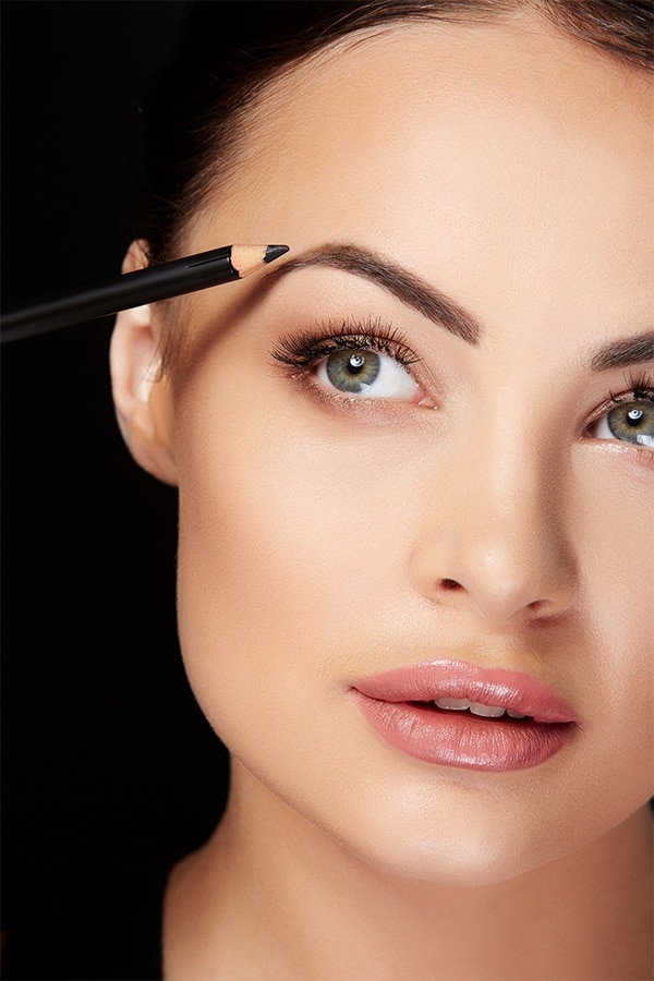 Woman applying eyebrow pencil