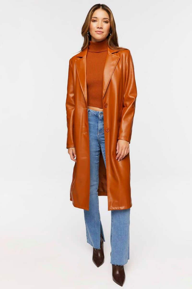 Model wears orange leather trench coat over jeans and t-shirt. 