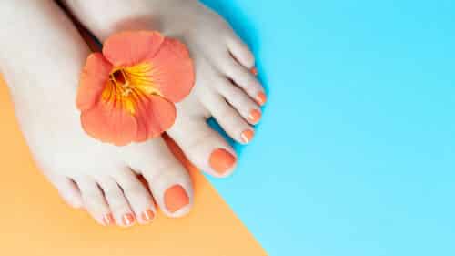 Orange pedicure with orange and blue background.