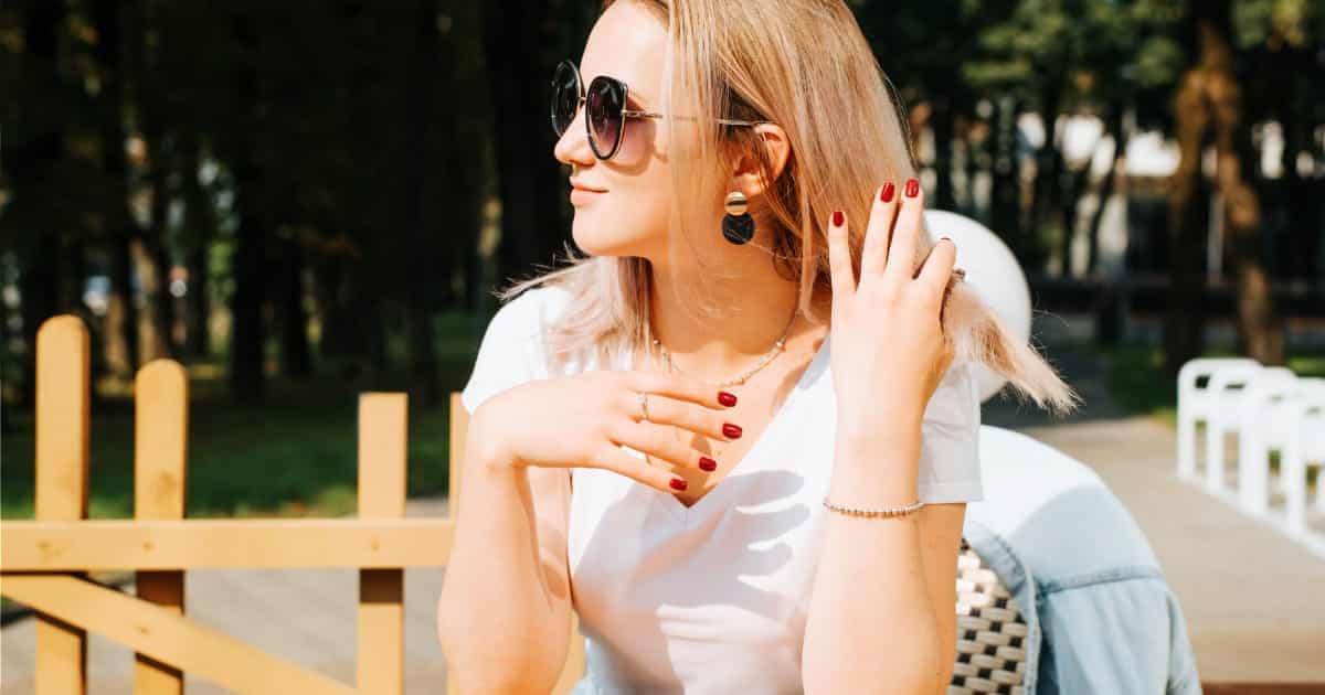 Woman sitting outside with pretty red manicure.