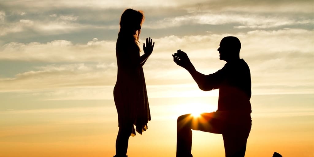 Man proposing to woman at sunset 