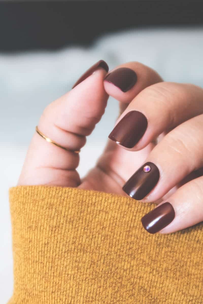 Close-up view of woman wearing red press-on nails.