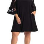 Model wearing black dress with sheer detail.