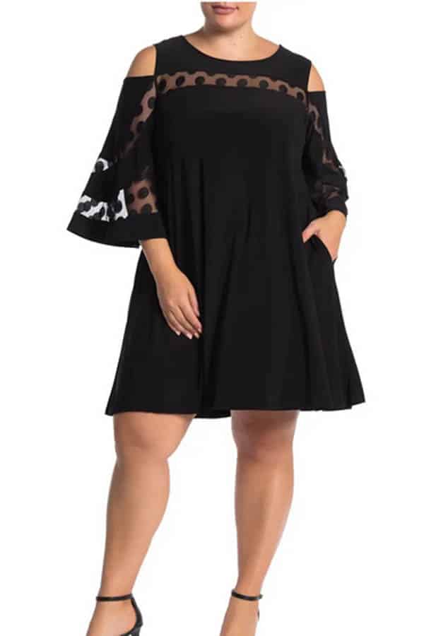 Model wears black date night dress with sheer pattern at neckline and on sleeves.