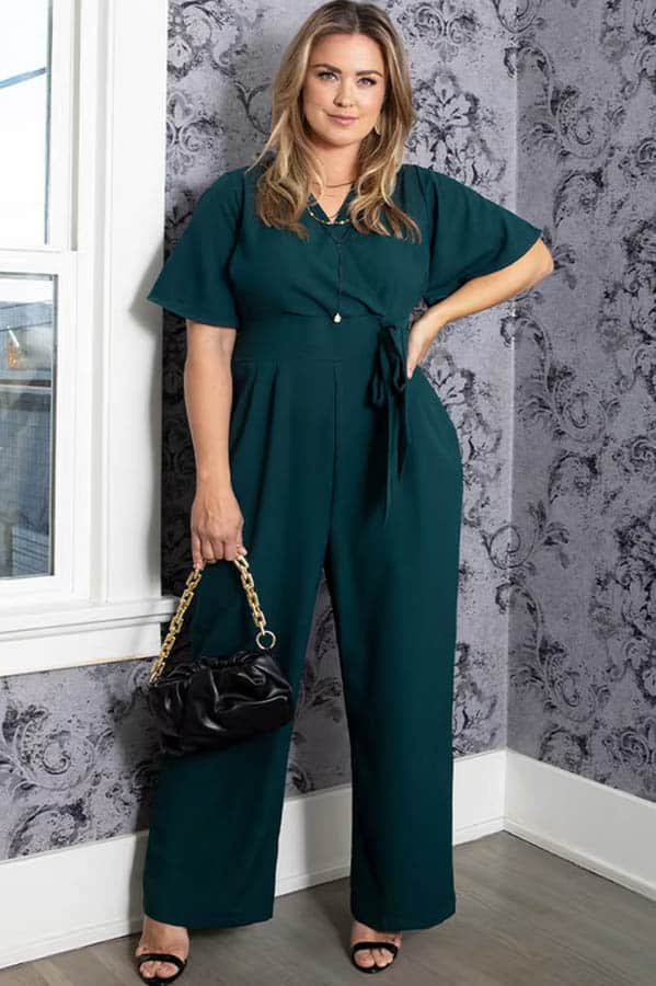 Model wears plus-sized jumpsuit in forest green.