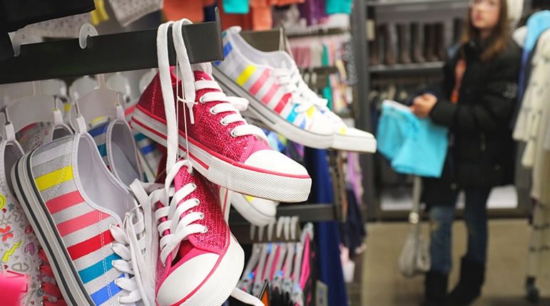 Young girl shopping in shoe store to represent Payless Shoes.