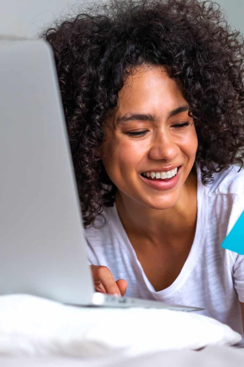 Smiling woman shopping online to represent why shop Amazon.