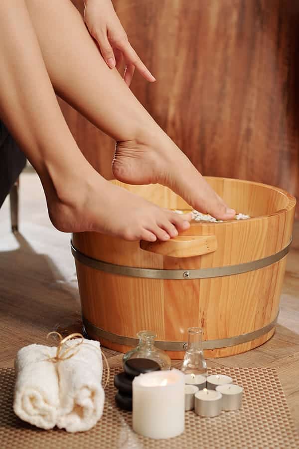 Woman dunking her feet in a basin of water for her at-home pedicure.