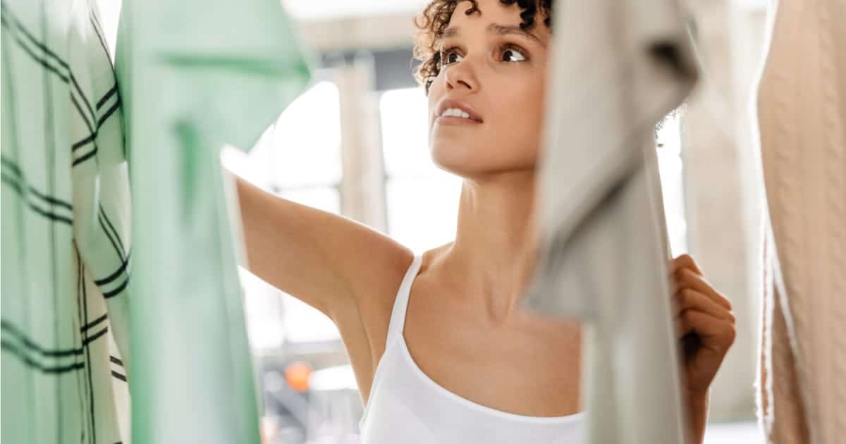 Woman looks through closet at home.