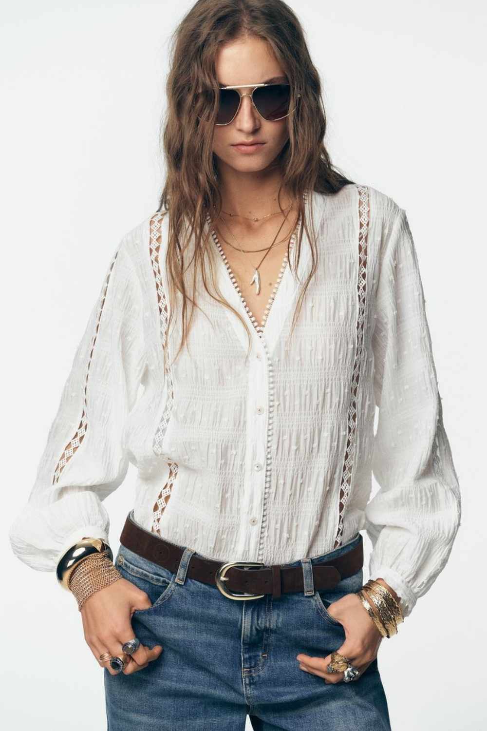 Model wears textured top with oversized jeans and chunky accessories 