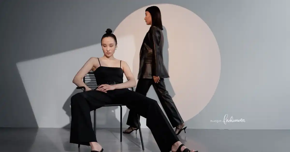 Two woman wearing all-black outfits against geometric background.