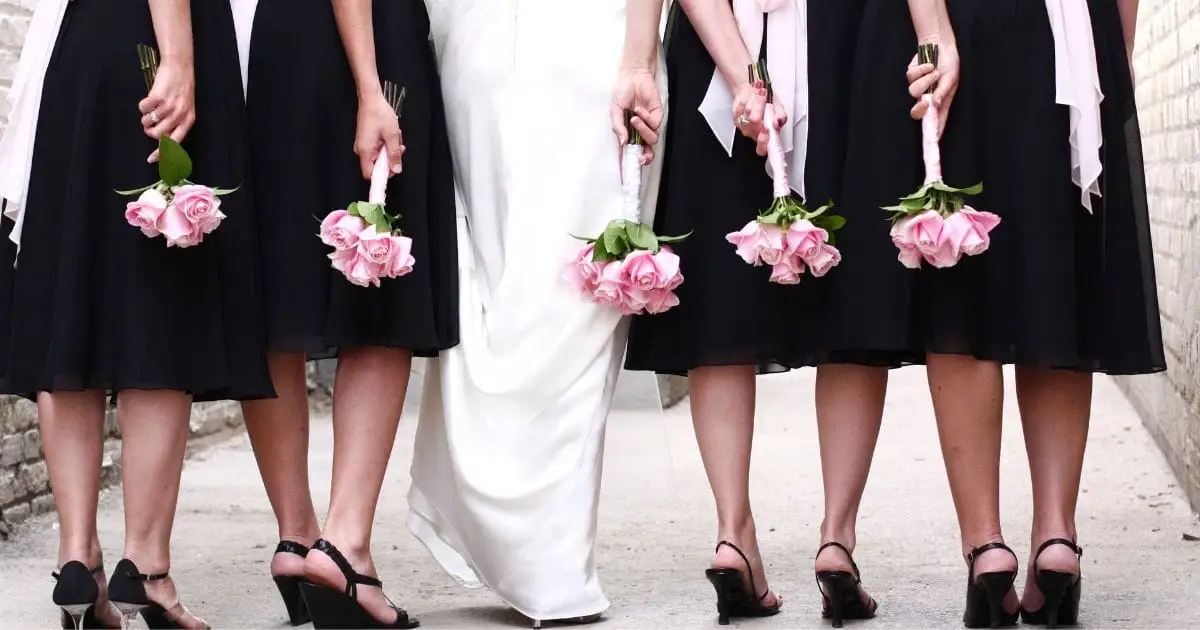 View from behind of bridal party wearing black dresses and bride.