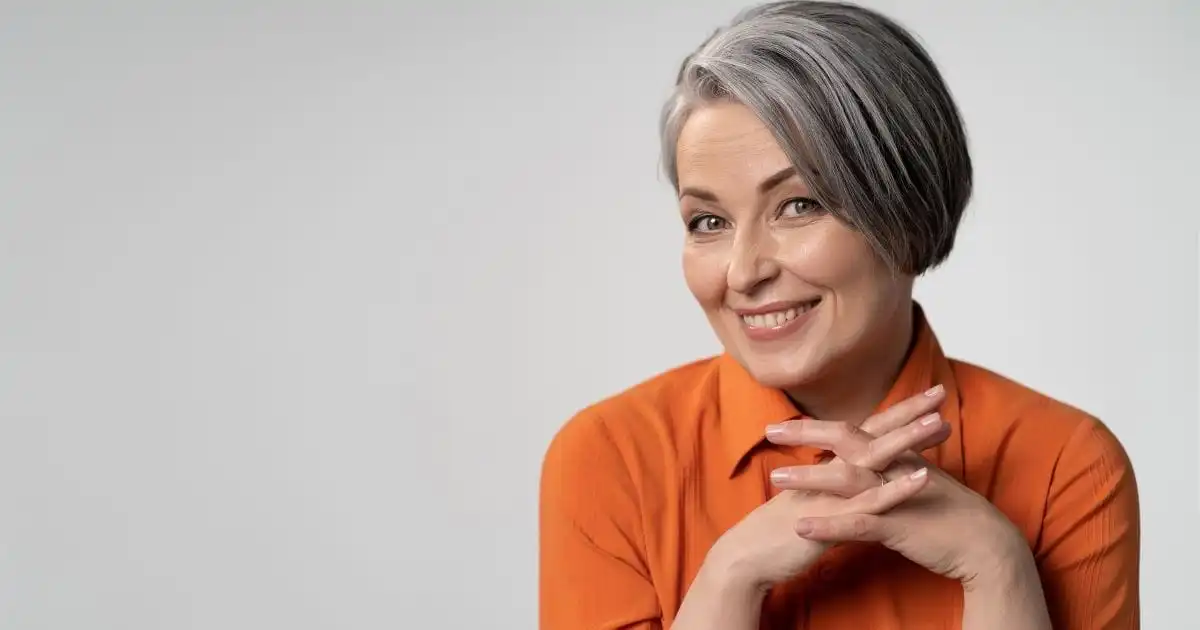 Smiling older woman wearing orange sweater.